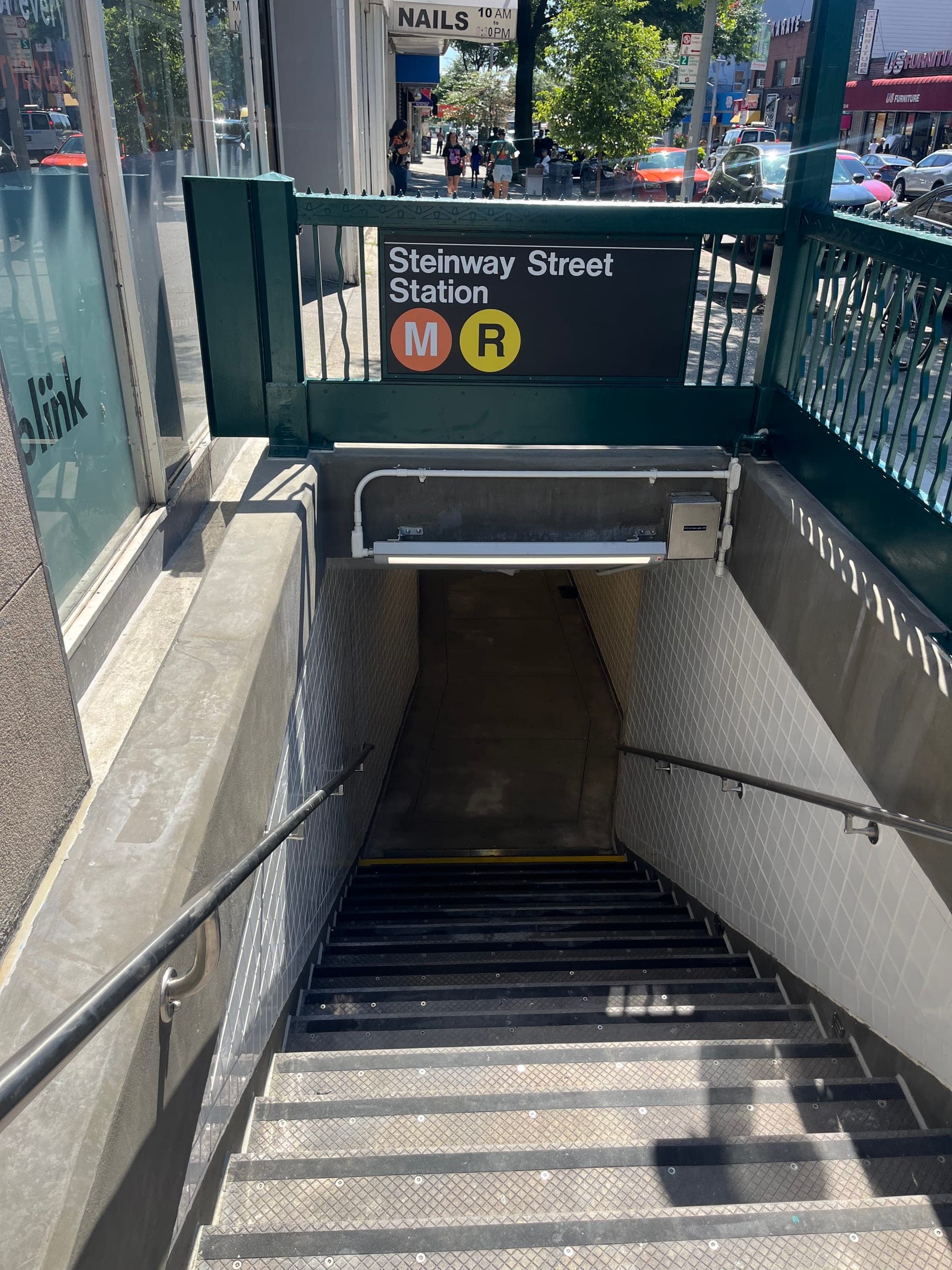 MTA Contract A-37851 — Stair Replacement (JV) — Completed Steinway Street Station stair entrance with new tile walls, glass guardrails, and signage